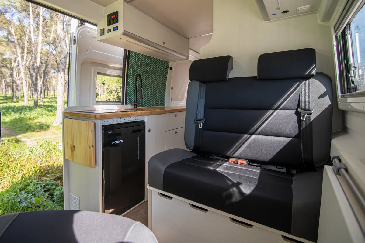 Interior de camper Fabricamper con mobiliario fijo profesional: armarios, cama y zona de comedor