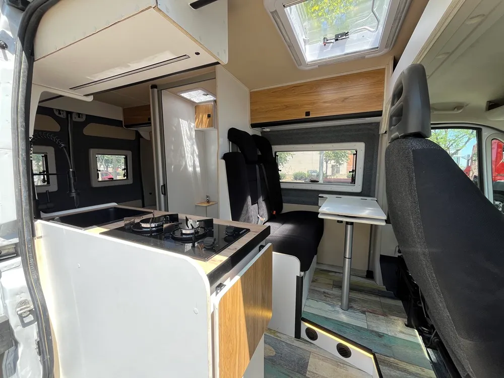 Cocina de la camperización Ducato L2H2 con encimera de madera mirando hacia la cabina