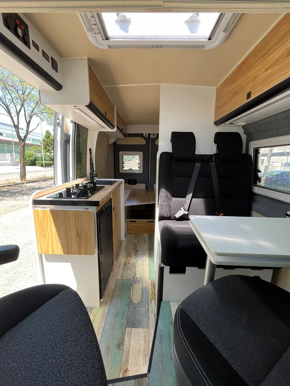 Interior de la camper Ducato L2H2 con suelo vinílico verde envejecido y muebles blancos