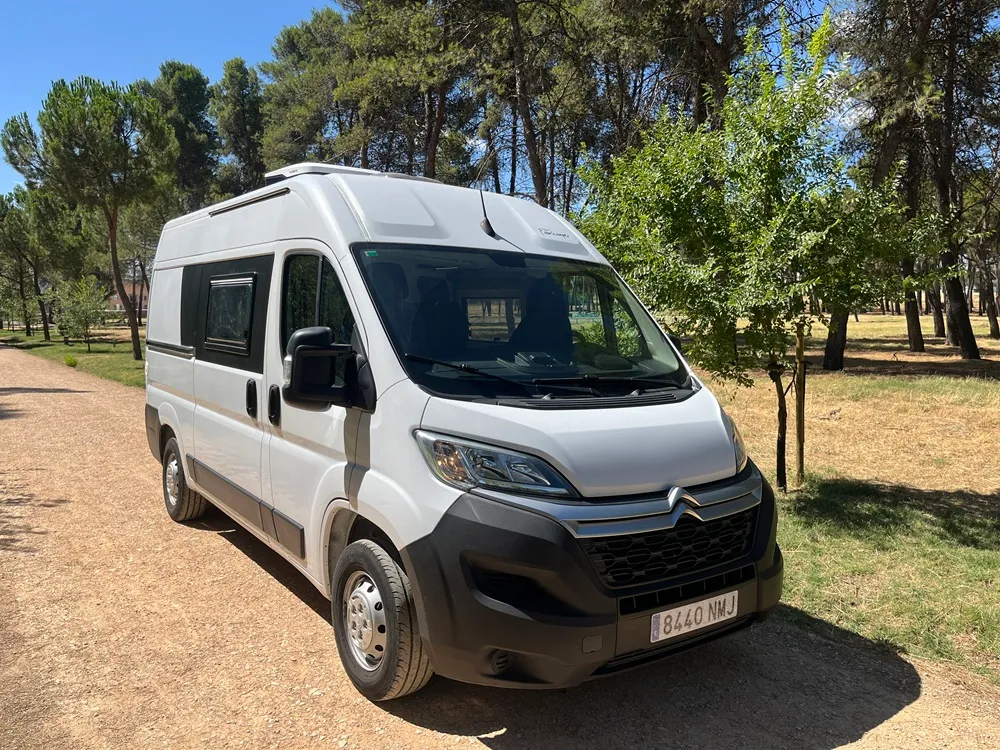 Citroën Jumper L2H2 camperizado por Fabricamper en blanco, vista frontal tres cuartos entre pinos