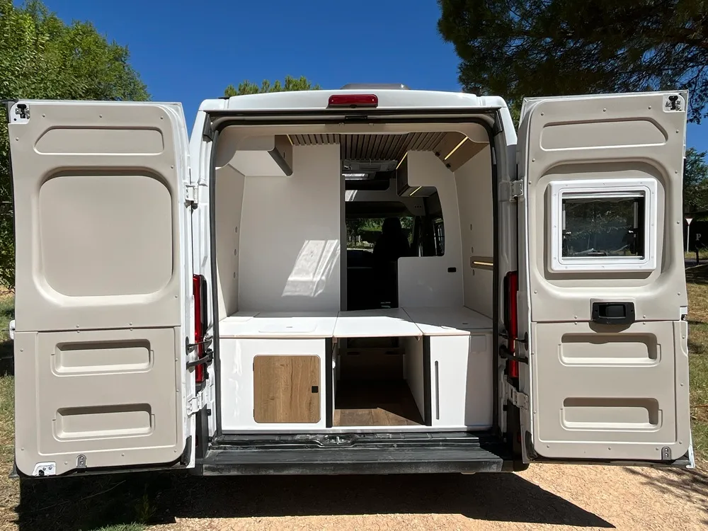 Puertas traseras abiertas de la camper Jumper L2H2 con maletero y base de la cama