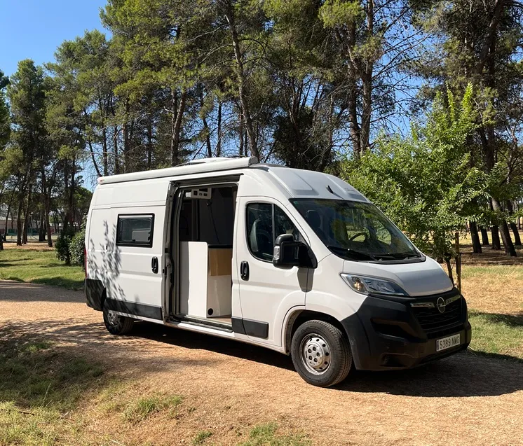 Camper Opel Movano L3H2 con la puerta lateral abierta y el interior en blanco y madera