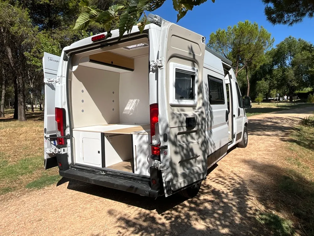 Puertas traseras abiertas de la camper Movano L3H2 con la cama y el maletero inferior