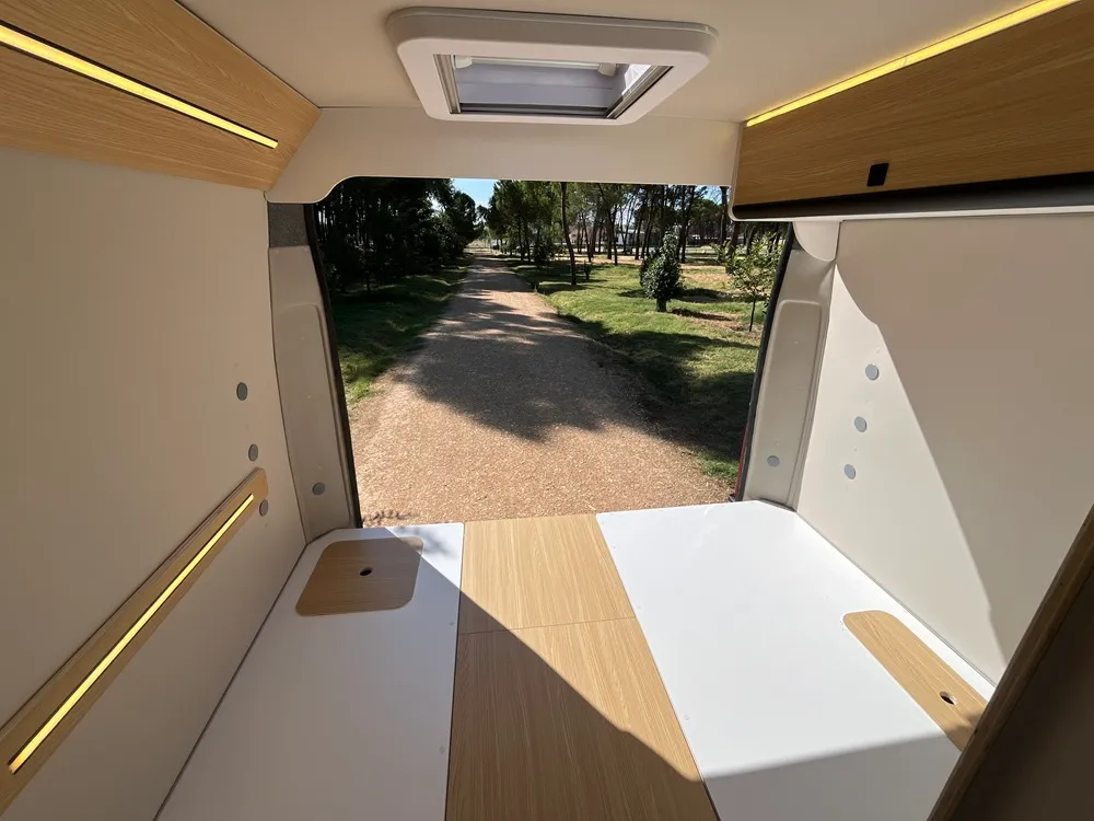 Base de la cama de la camper Movano L3H2 con las puertas traseras abiertas al pinar